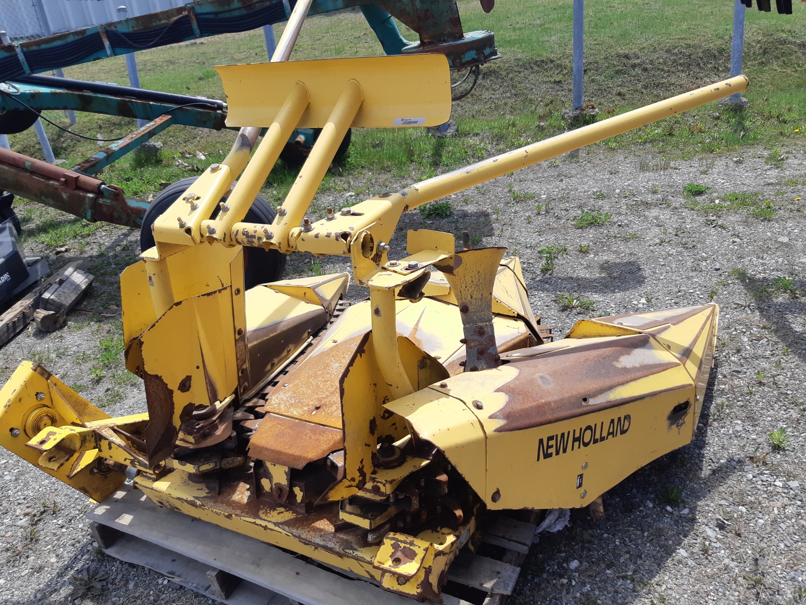 A yellow and rusted piece of farm equipment, labeled 