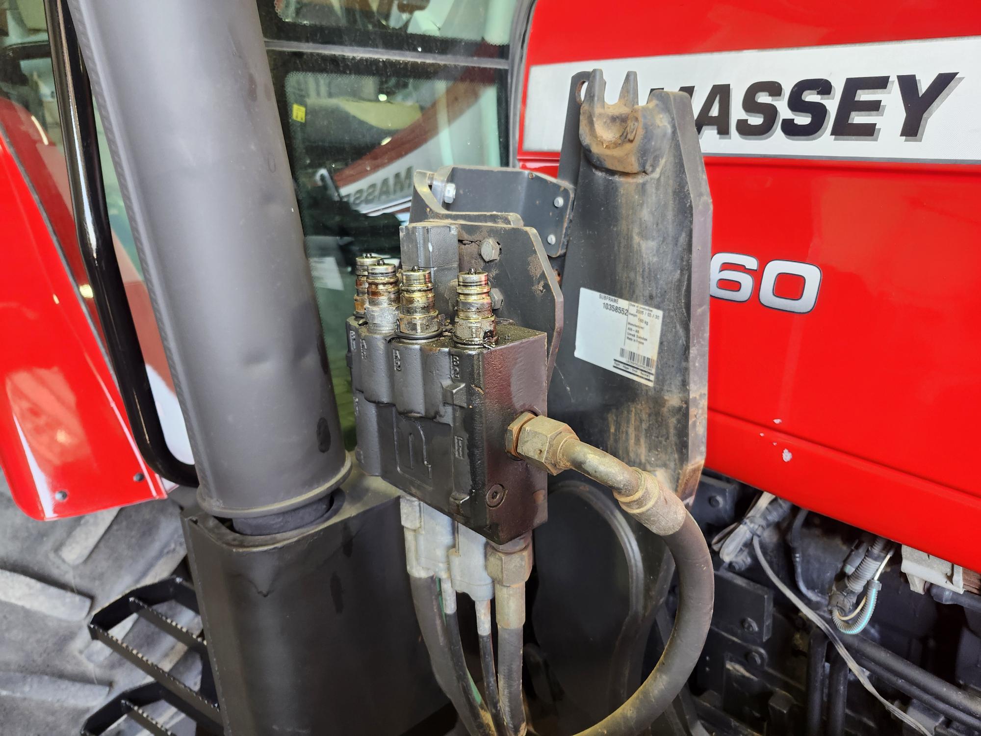 Gros plan des connecteurs de tuyaux hydrauliques fixés à une vanne de commande sur un tracteur Massey Ferguson 660 rouge.