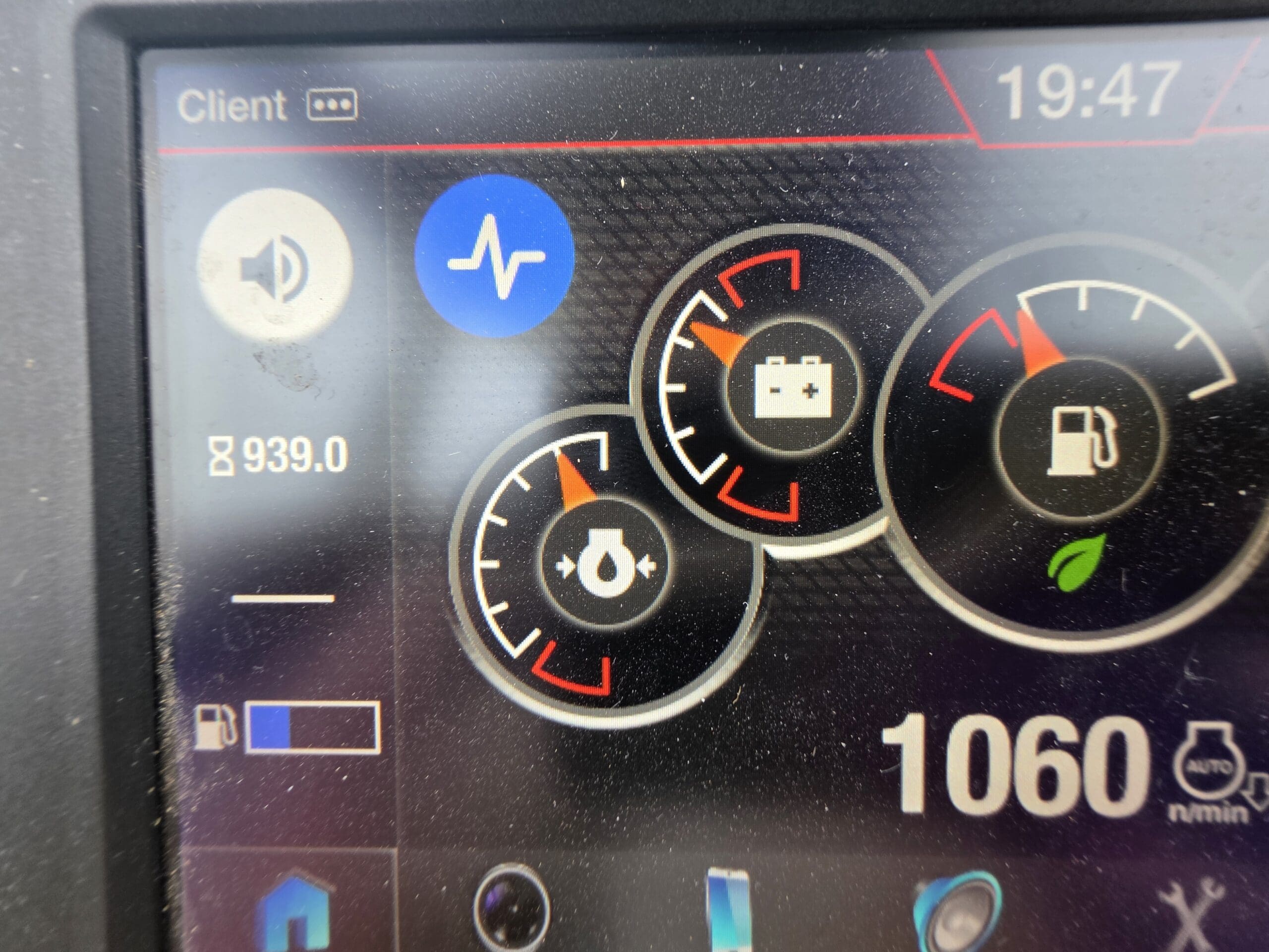 Un tableau de bord numérique affiche diverses jauges, notamment des indicateurs de batterie et de carburant, une icône de signal bleu, une lecture de 939,0 et une heure de 19:47 dans le coin supérieur droit.