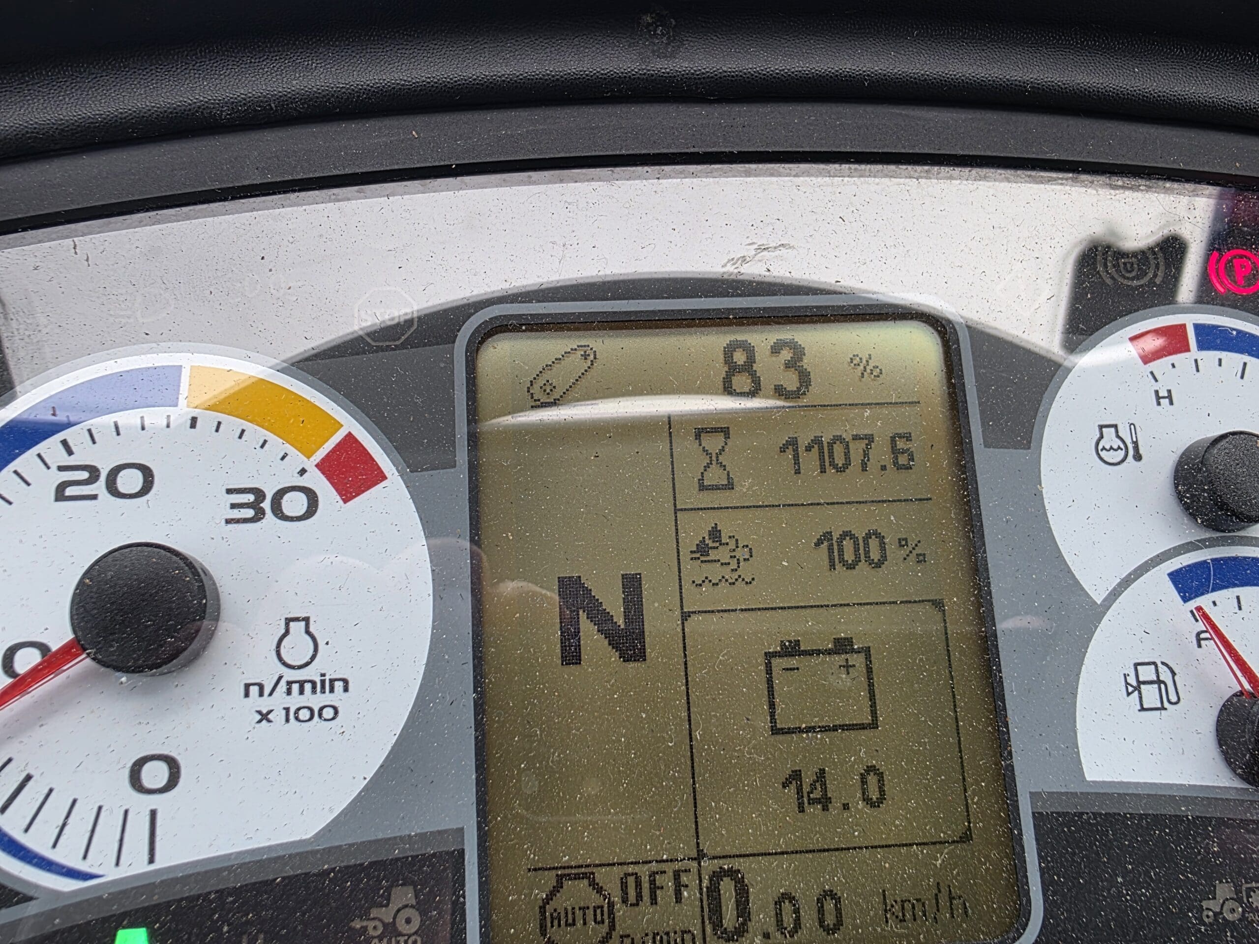 Gros plan d'un tableau de bord numérique de véhicule affichant 83 % de batterie, 1107,6 heures, 100 % de liquide de refroidissement, point mort (« N »), 14,0 volts et des jauges analogiques de régime, de carburant et de température.