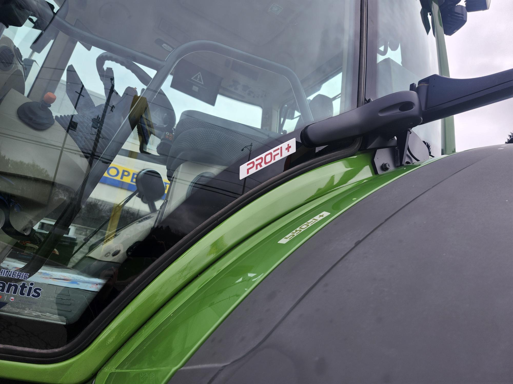 Gros plan de la cabine d'un tracteur vert, montrant l'étiquette « PROFI+ » sur la fenêtre et une partie du volant et du tableau de bord à l'intérieur.