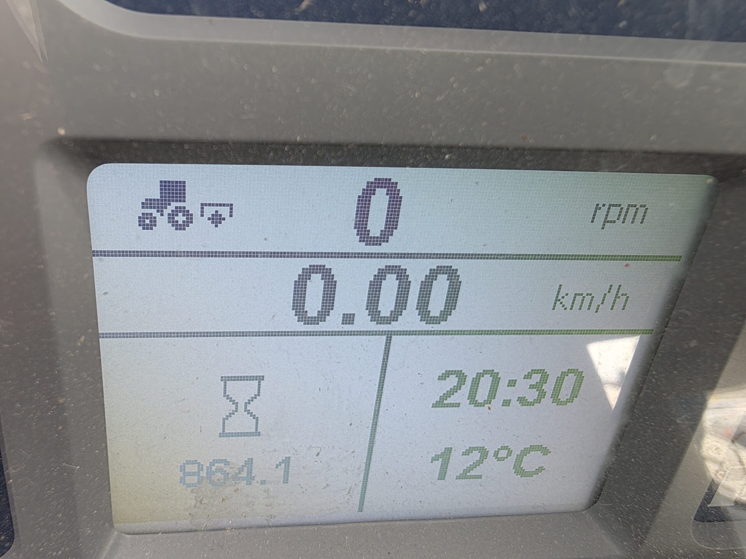 Un écran numérique affiche 0 tr/min, 0,00 km/h, 864,1 heures, une icône de sablier, l'heure 20:30 et la température 12°C. Les icônes du tracteur et de la remorque apparaissent dans le coin supérieur gauche.