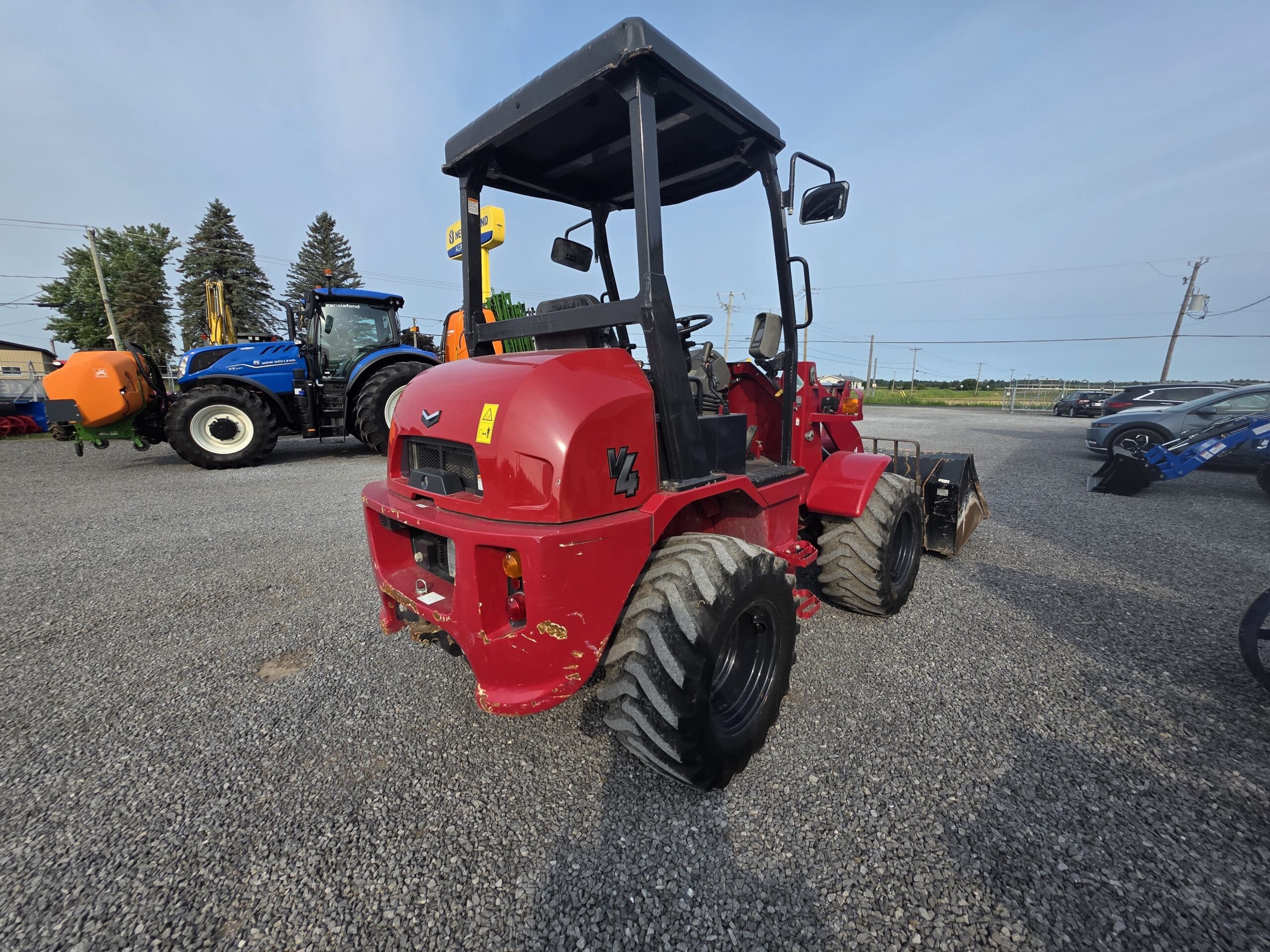 Un tracteur rouge garé sur du gravier.