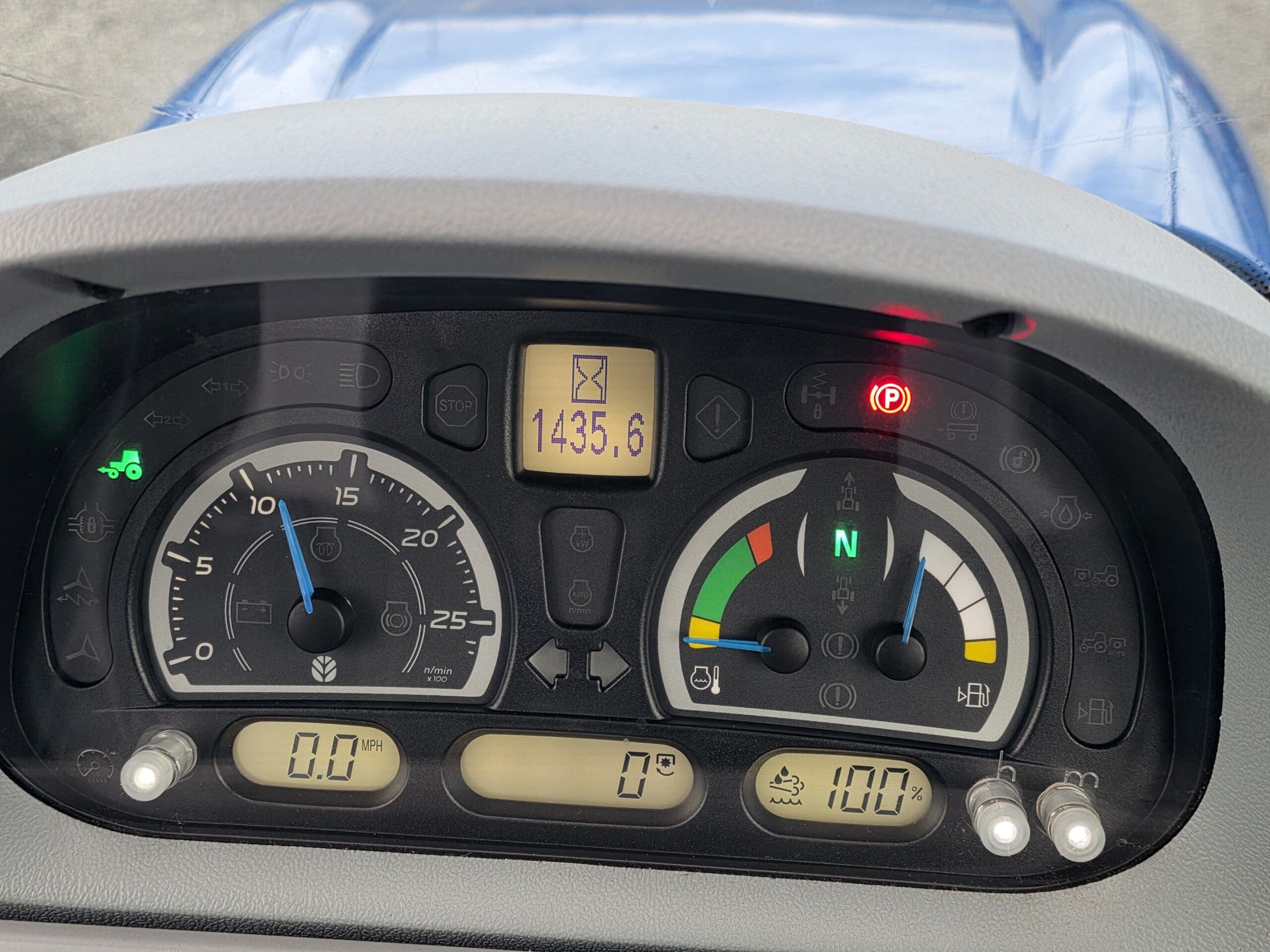 Gros plan du tableau de bord d'un tracteur montrant les jauges de vitesse, de carburant et de température. L'affichage numérique indique 