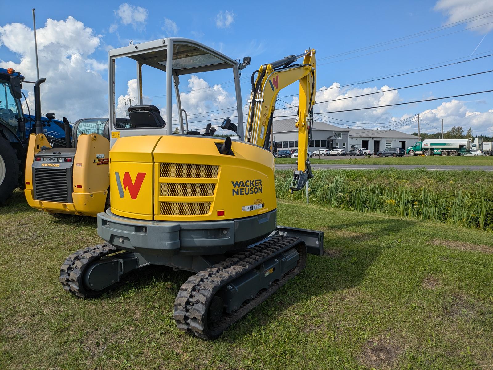 Wacker Neuson EZ36 vu de trois quarts avant, logo Wacker Neuson bien visible sur le capot, isolée sur le gazon sous un ciel dégagé