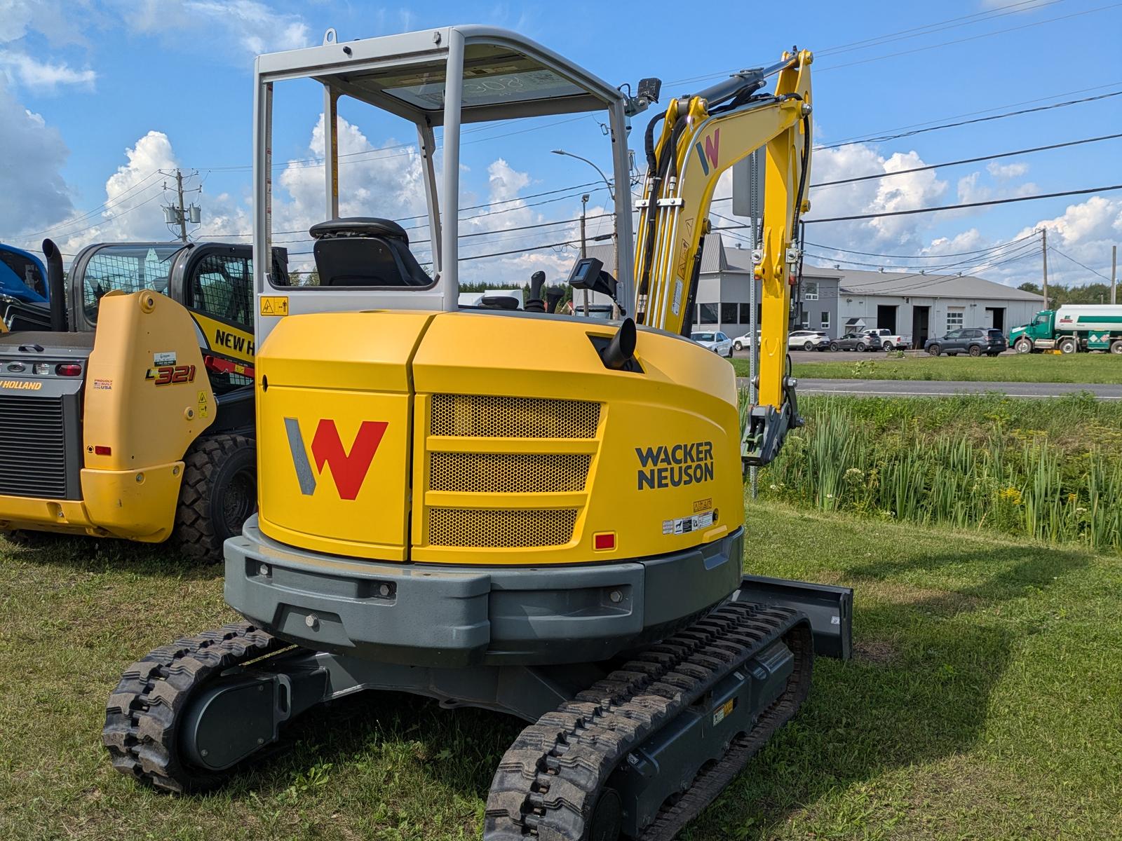 Wacker Neuson EZ36 vu de trois quarts avant, logo W rouge sur le capot, godet visible à l'avant