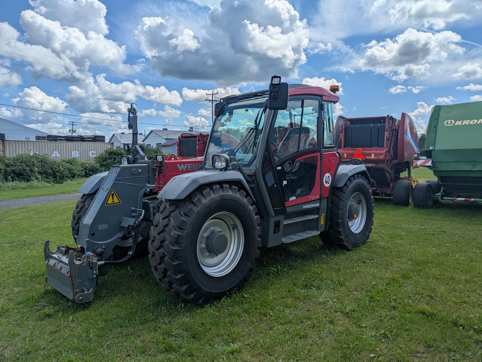 Weidemann 2080T vu de trois quarts avant-gauche avec une benne noire attelée à l'avant