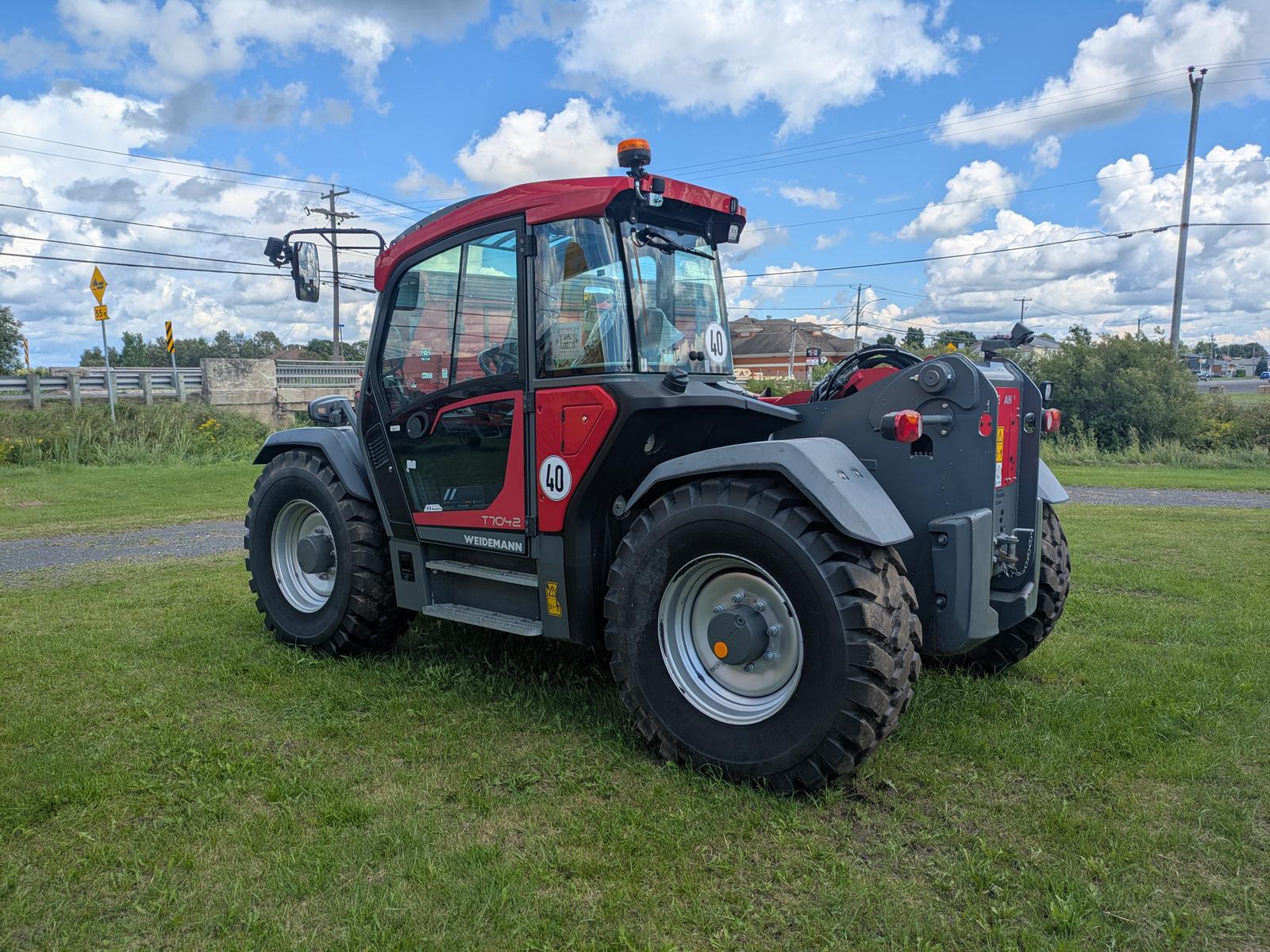 Weidemann 2080T vu de trois quarts avant-droit, cabine vitrée bien visible, gazon en arrière-plan