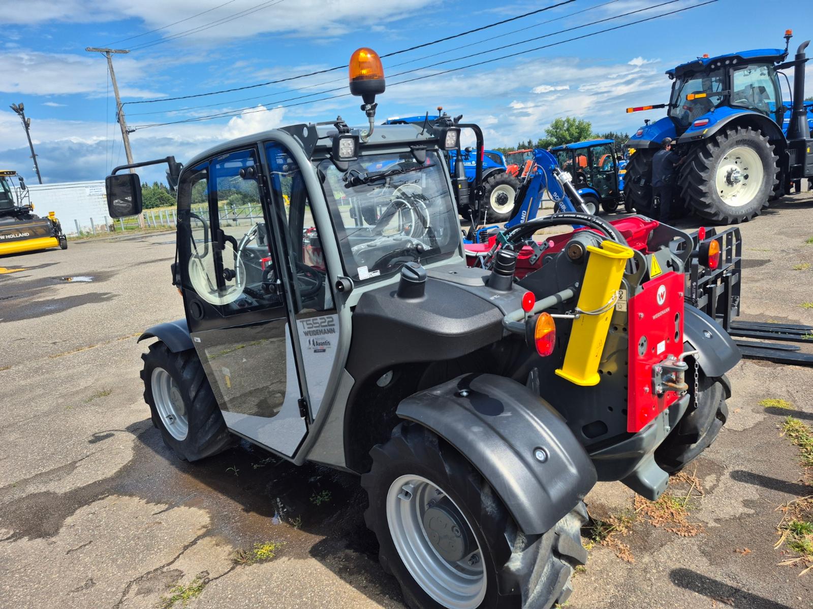 Weidemann T5522 vu de trois quarts arrière-droit, carrosserie grise avec attache rouge et jaune à l'avant