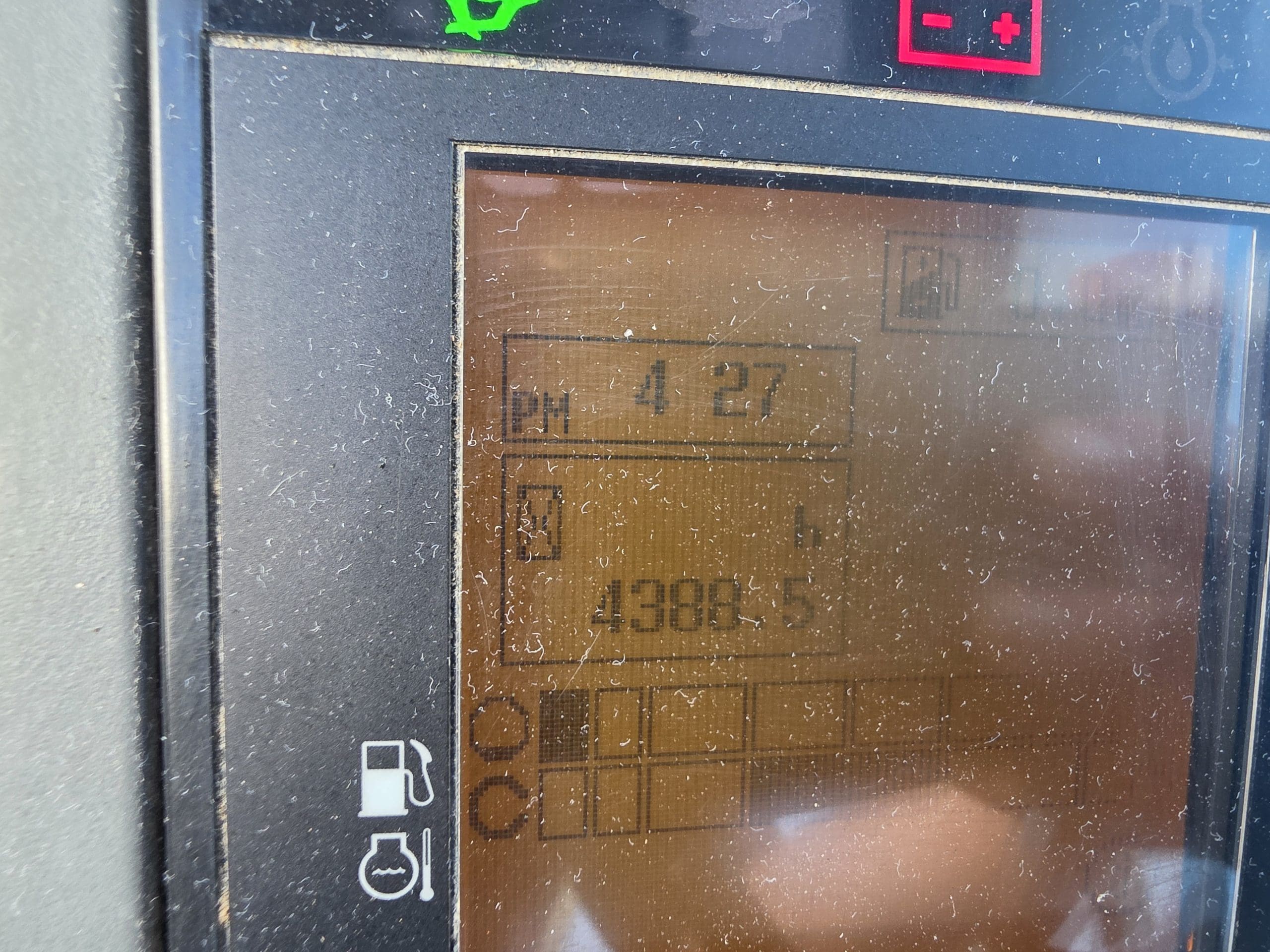 Un gros plan sur l'écran poussiéreux du tableau de bord d'un véhicule indique qu'il est 16 h 27 et que le compteur kilométrique affiche 4 385,5. Des icônes représentant le niveau de carburant et d'autres éléments sont également visibles à l'écran.