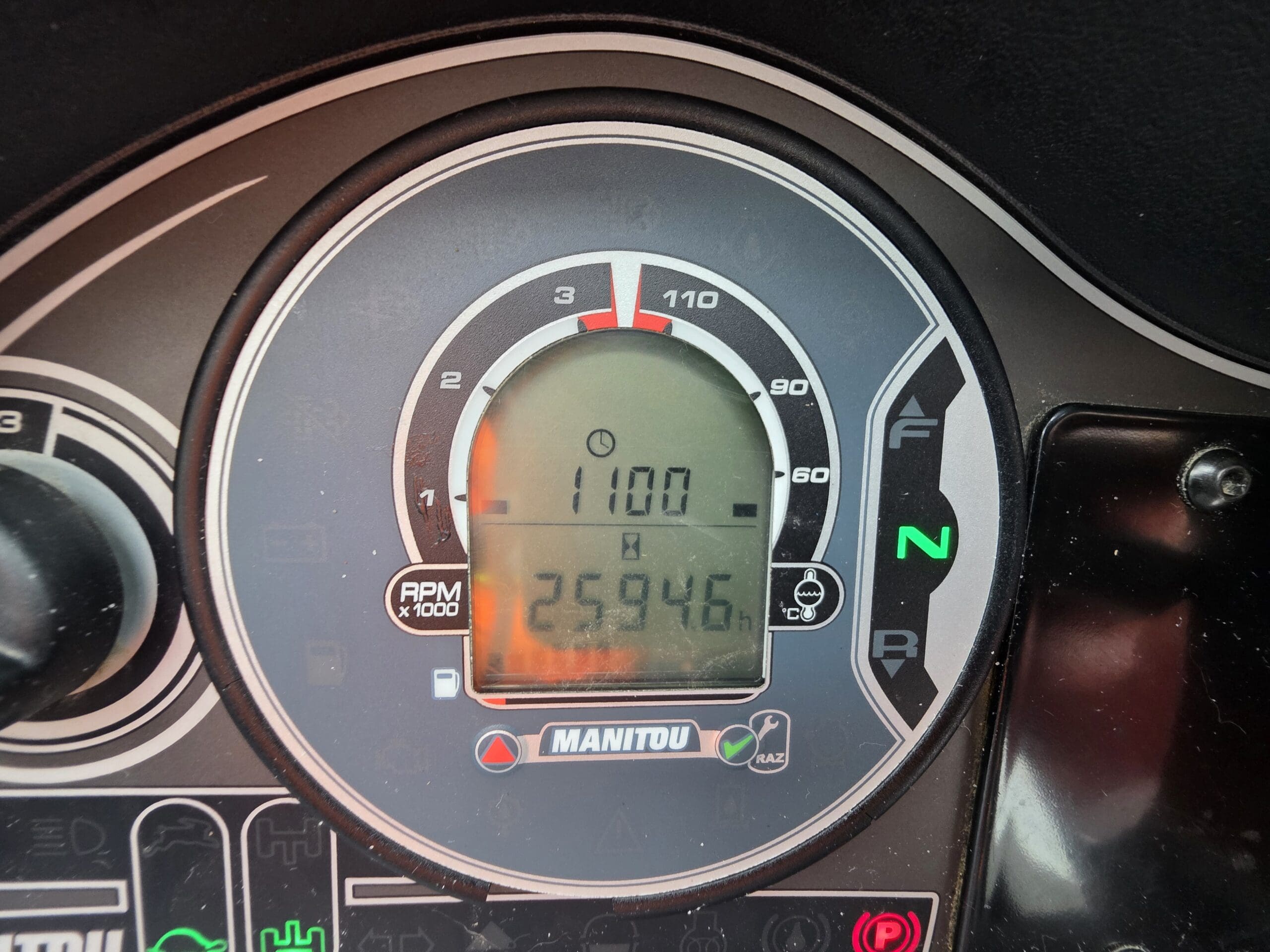 Gros plan sur le tableau de bord d'un véhicule Manitou indiquant 1 100 tr/min, la jauge de carburant au maximum et un kilométrage de 2 594,6 miles. Le voyant de point mort « N » est allumé en vert.