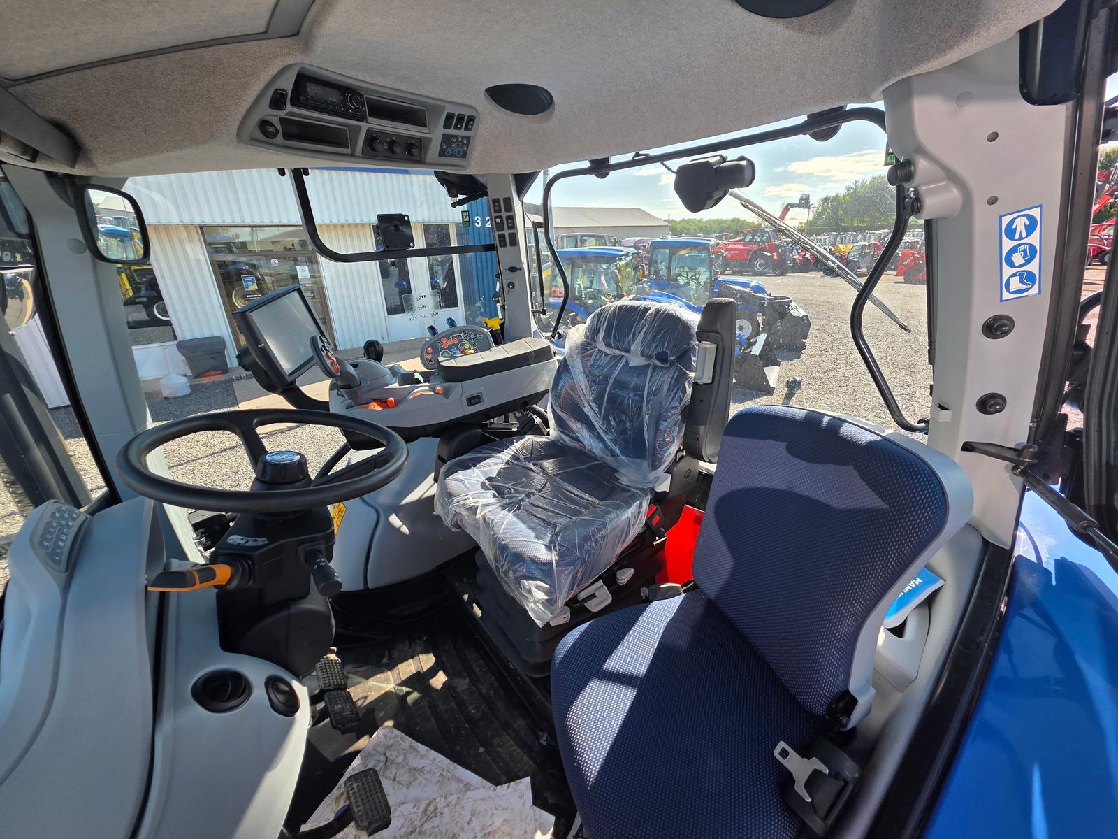 New Holland T5, intérieur de la cabine, siège protégé d'une housse plastique et écran de bord allumé