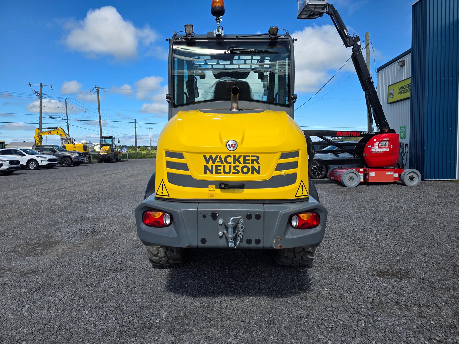 Wacker Neuson WL52 vu de trois quarts arrière-droit, inscription WL52 visible, bâtiment du concessionnaire en arrière-plan