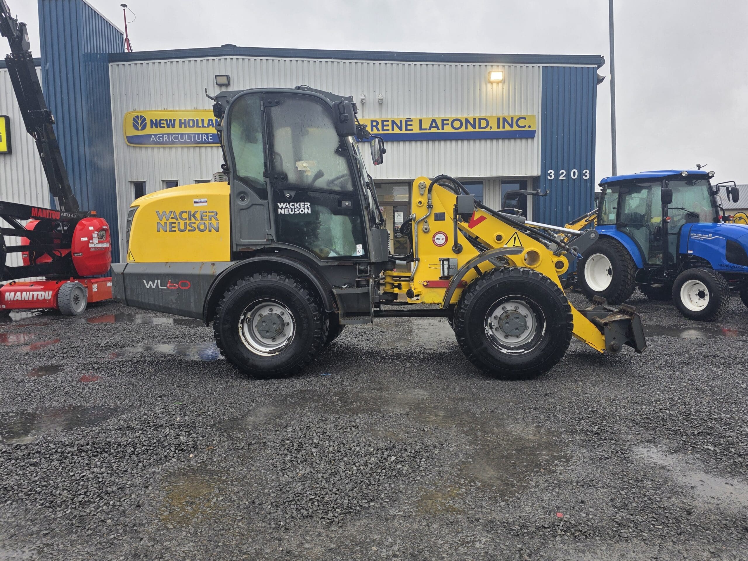 Une chargeuse sur pneus Wacker Neuson jaune garée devant une concession René Lafond, Inc.