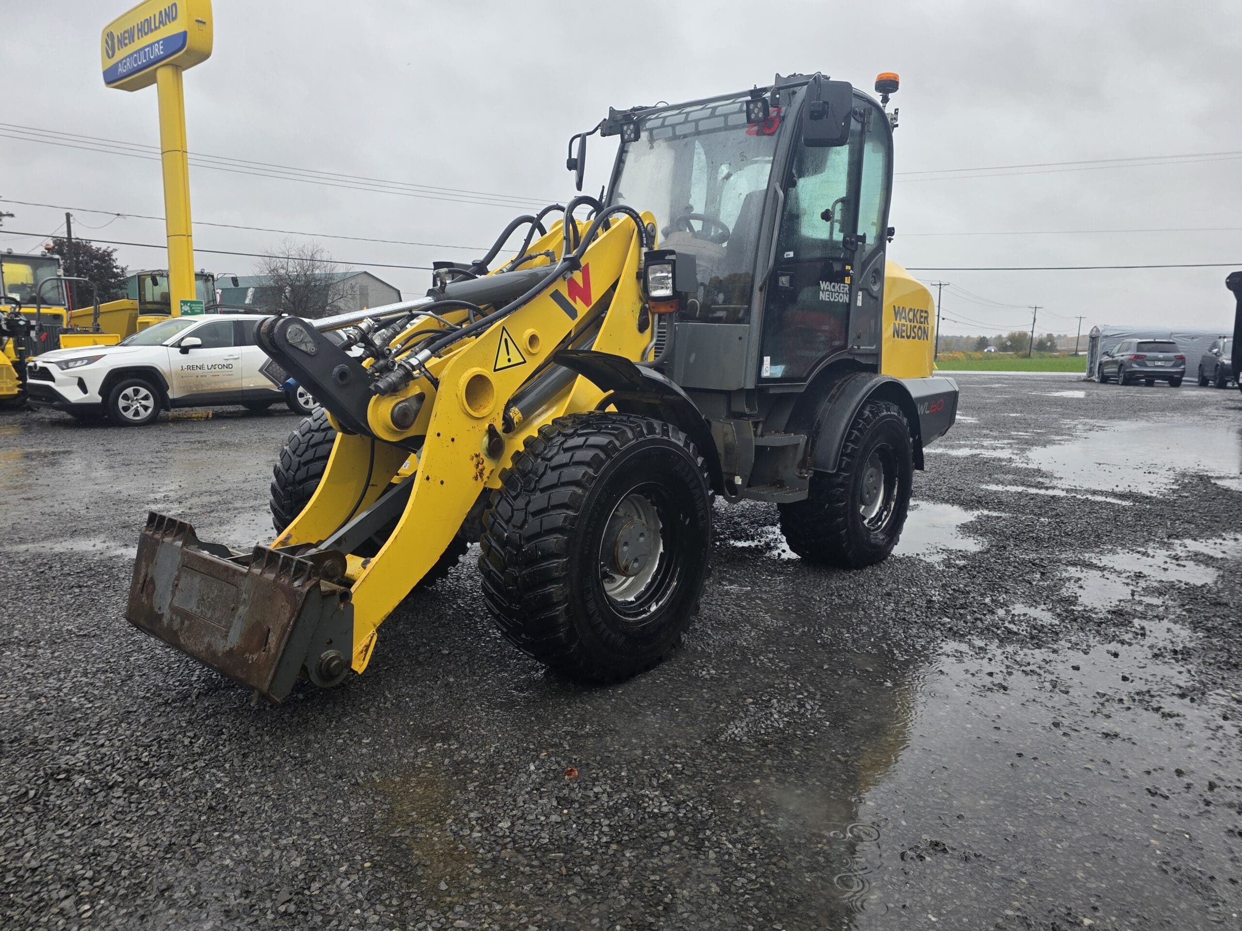Une chargeuse sur pneus Wacker Neuson jaune garée sur un terrain en gravier.