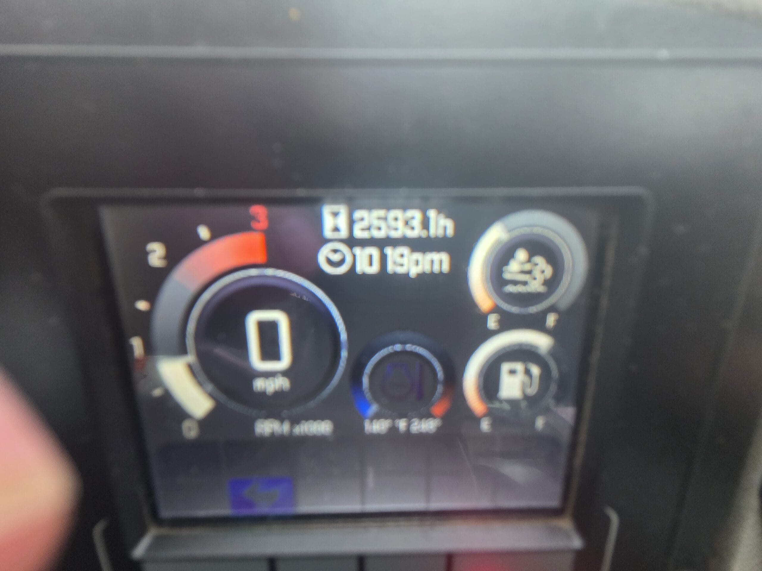 Un tableau de bord numérique indiquant une vitesse de 0 mph, 2 593,1 heures de fonctionnement du moteur et l'heure : 22 h 19.