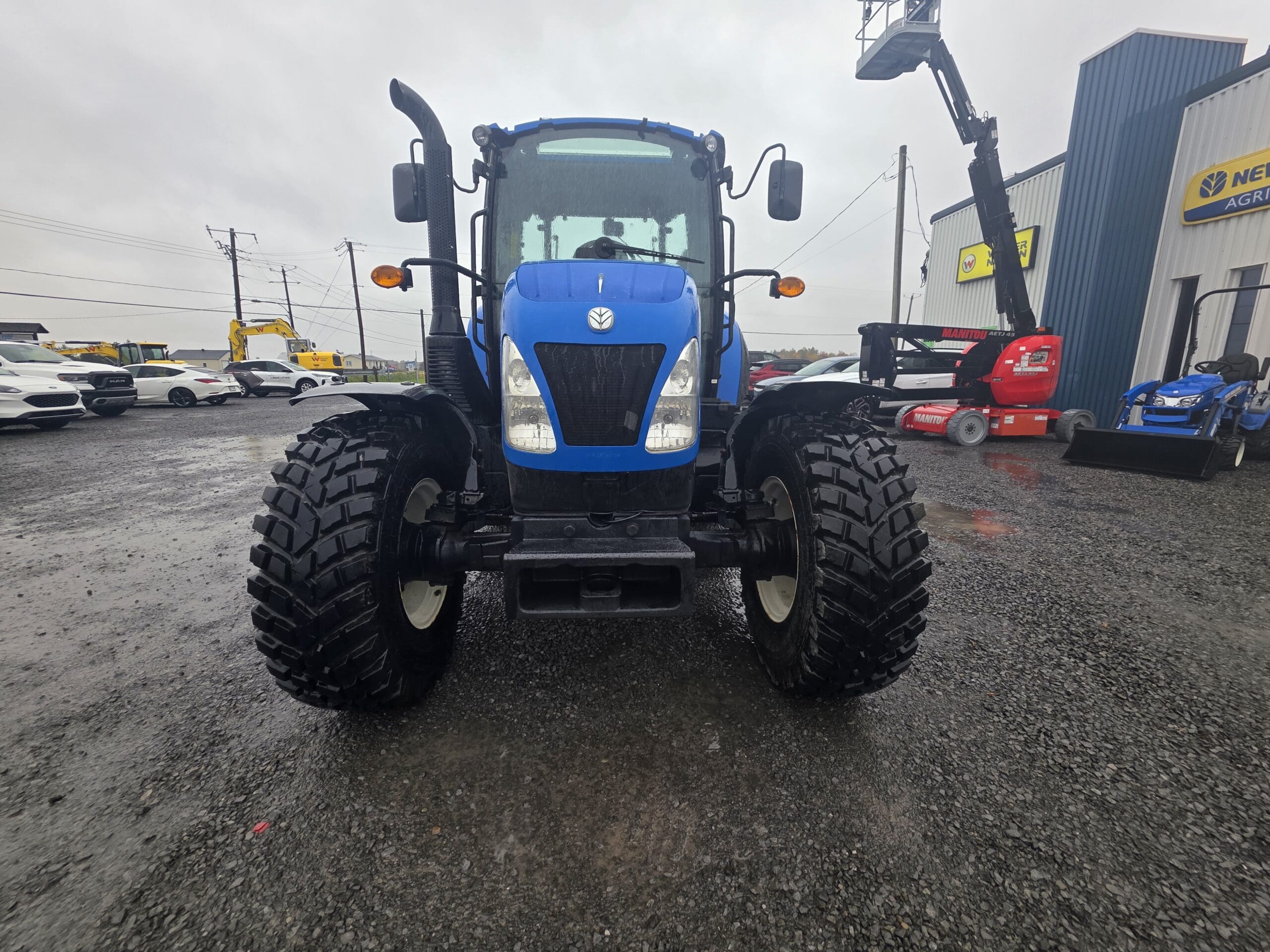 Un tracteur New Holland bleu garé dans un parc de matériel.