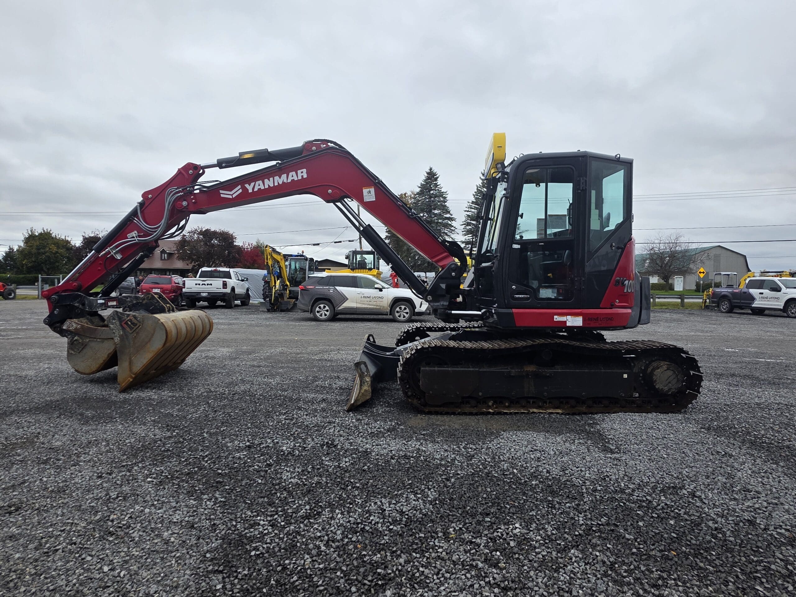 Une pelleteuse sur chenilles Yanmar rouge garée sur un terrain en gravier.