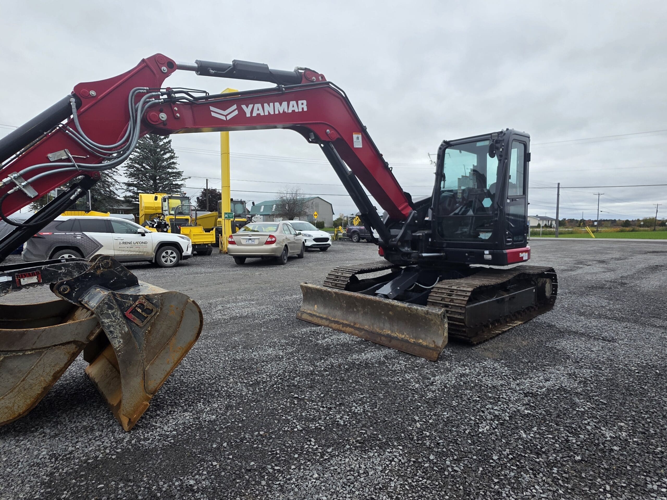 Une pelleteuse à chenilles Yanmar rouge garée sur un terrain en gravier.